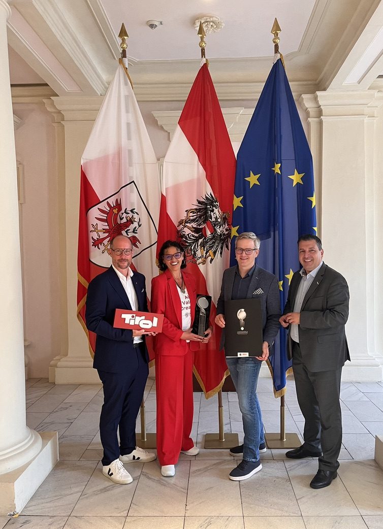 Sabine Singer mit Award vor Tirol-, Österreich- und EU-Fahne